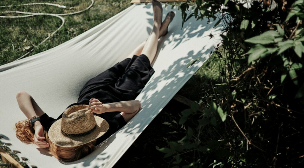 A man laying in a hammock with a hat on